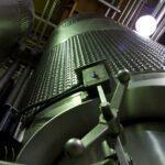 Low-angle shot of large stainless steel tanks inside a modern industrial facility.
