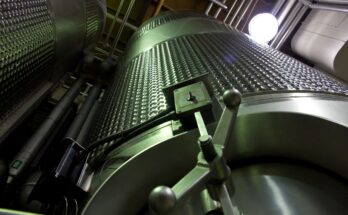 Low-angle shot of large stainless steel tanks inside a modern industrial facility.