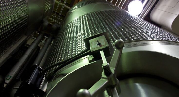 Low-angle shot of large stainless steel tanks inside a modern industrial facility.